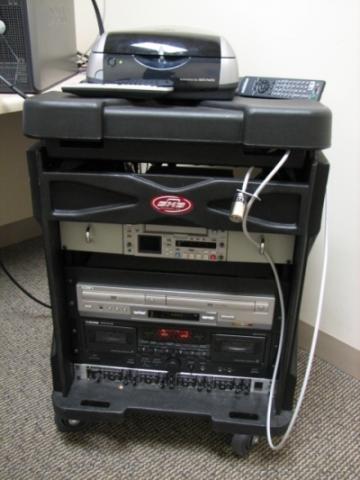 Image of media cart with VCR/DVD combo unit, a DV tape player/recorder, a cassette deck, and a headphone amp.